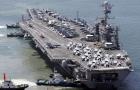 EL GIGANTE. Barcos mueven el portaaviones George  Washington hasta su atracadero en el puerto de Busan. REUTERS