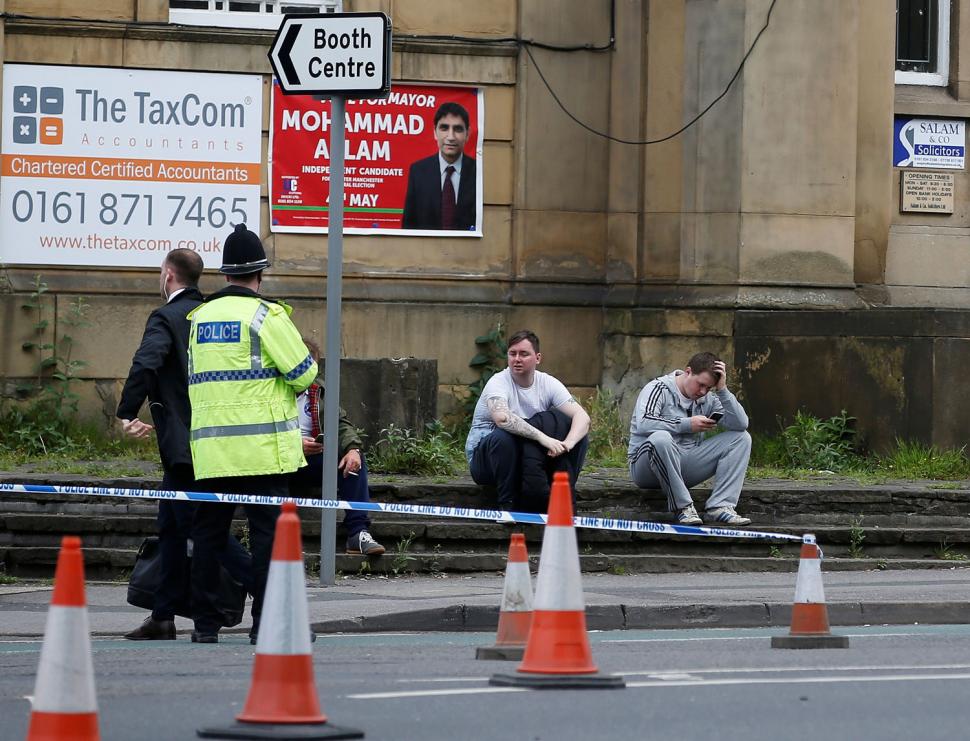 La gente se sienta al lado de un cordón de la policía cerca de la Arena de Manchester. REUTERS