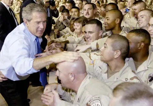 ENTRE OVACIONES. Bush bromea con la cabeza calva de uno de los soldados norteamericanos en Qatar.
