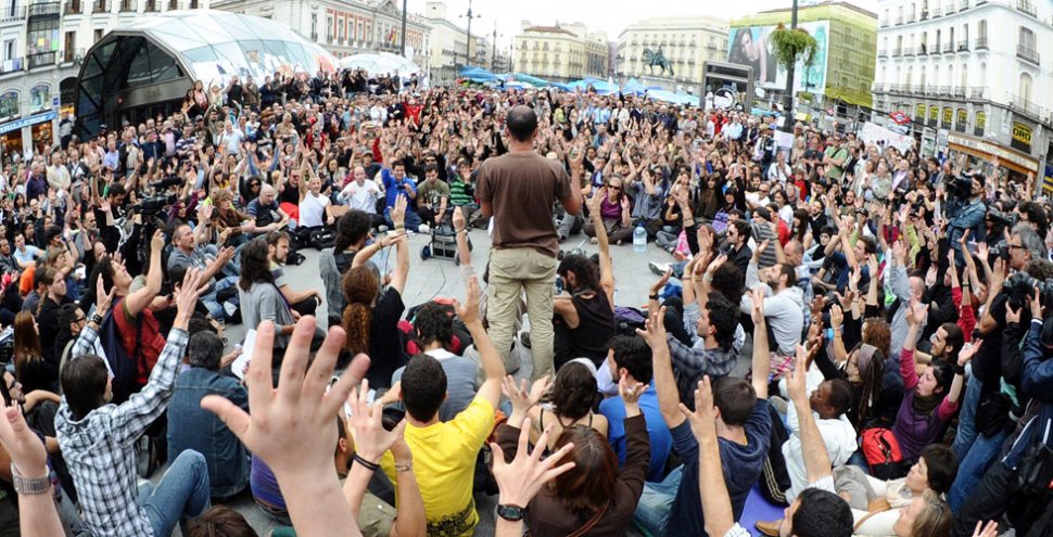 ASAMBLEA. Los manifestantes levantaron sus manos para votar por la continuidad de la protesta, en la Puerta del Sol de Madrid. AFP