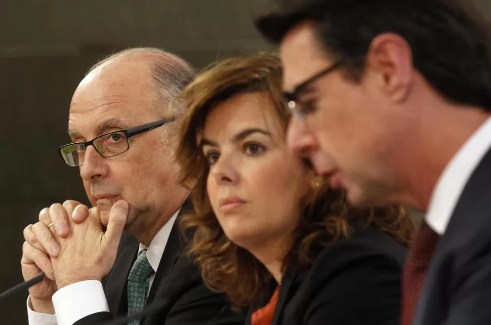 ANUNCIOS. Los ministros Montoro y Soria, y la vicepresidenta Santamaría explican los alcances del ajuste. REUTERS