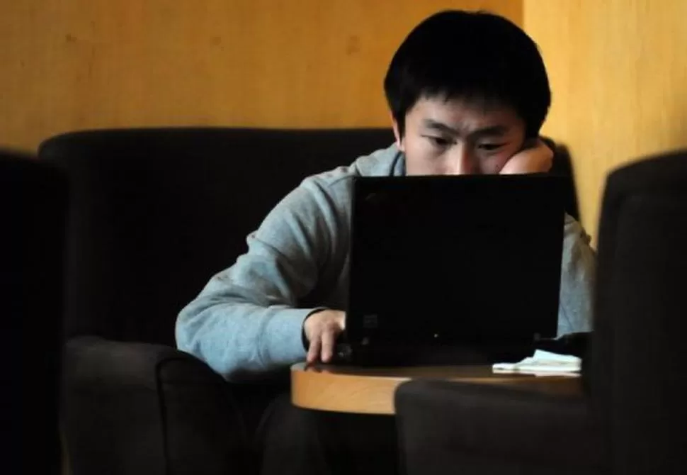 LIMITACIONES. Un habitante de Pekín accede a Internet en un bar. AFP