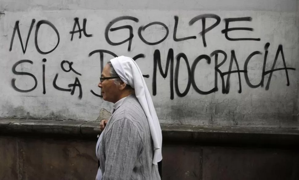 EN ASUNCIÓN. Una monja camina por una calle del centro de la capital paraguaya. En las paredes se evidencia el repudio a la destitución de Lugo. REUTERS