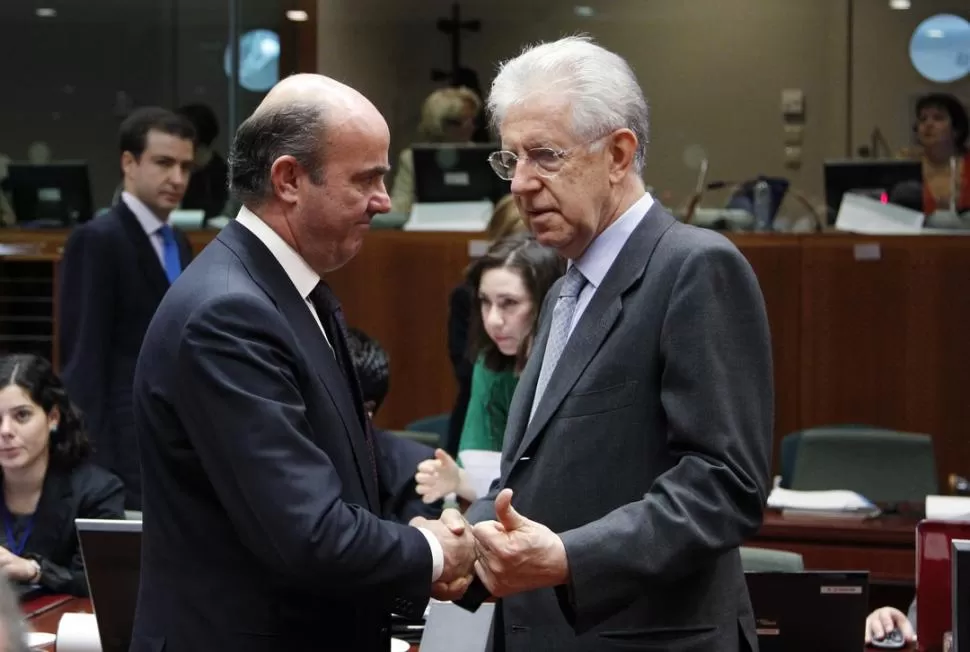 COMPARTEN PENAS. El ministro de Economía español, Luis de Guindos, saluda al primer ministro italiano Mario Monti durante la sesión de Bruselas. REUTERS