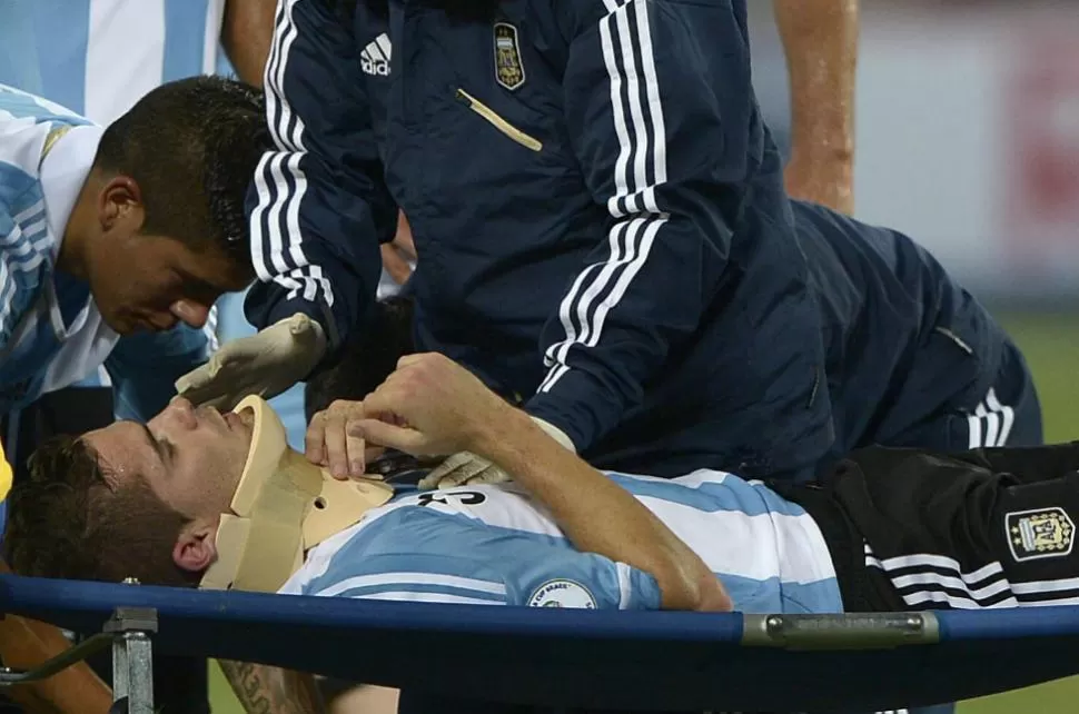 CONMOCION. El momento que sacan de la cancha a Fernando Gago tras recibir un golpe durante el partido de anoche. AFP 