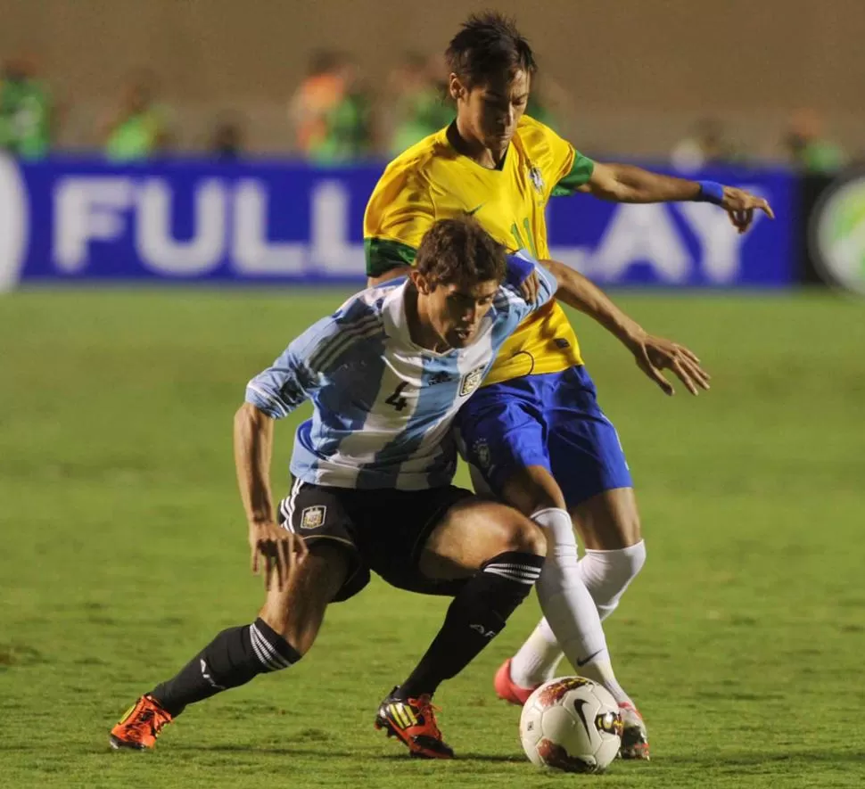 PARA TAPAR. Gino Peruzzi intenta frenar a Neymar para evitar que el crack brasileño se lleve la pelota. TÉLAM.
