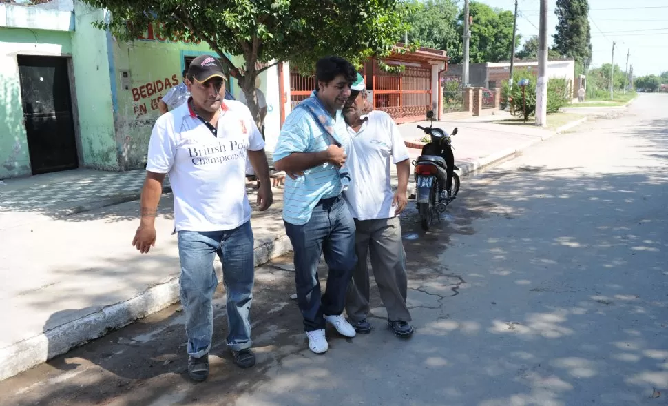 DOLOR. José González (de remera rayada) es acompañado por sus vecinos horas después del crimen de su hija, en la vereda de su casa, en Alderetes.