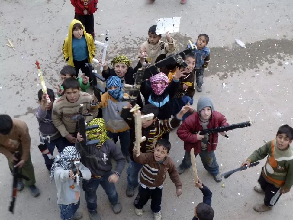 COMO SI FUESE UN JUEGO. Niños sirios se divertían ayer con armas de madera, mientras la violencia crece. REUTERS