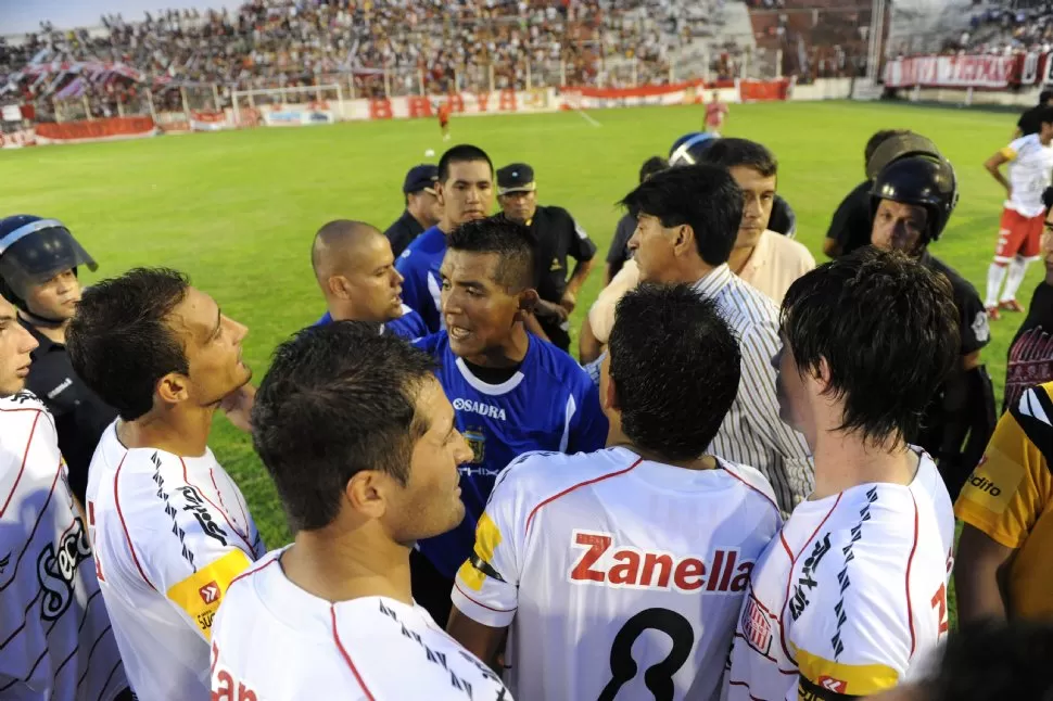 SIN RESPUESTA. Los jugadores de San Martín flanquearon al juez Acosta, de muy floja labor, para que les diera una respuesta de si seguía o no el partido. Demoró 30 minutos en suspenderlo. LA GACETA / FOTO DE FRANCO VERA