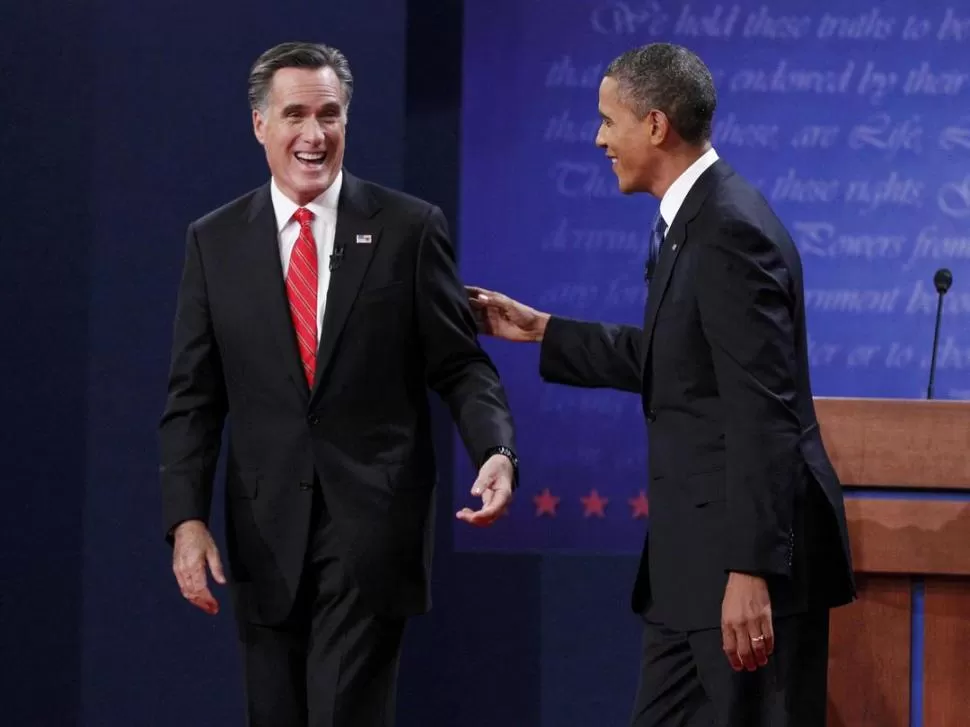 SONRISAS ANTES DEL DEBATE. El opositor Mitt Romney y el oficialista Barack Obama se saludaron para la televisión, previo a ocupar sus estrados. REUTERS