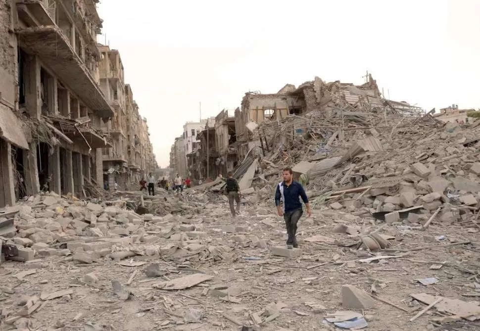 SECUELAS. Habitantes de Aleppo camina entre los destrozos provocados por las explosiones y los combates. REUTERS