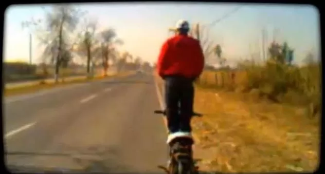 ARRIESGADO. El motociclista conduce su moto de pie en medio de la ruta. CAPTURA DE VIDEO