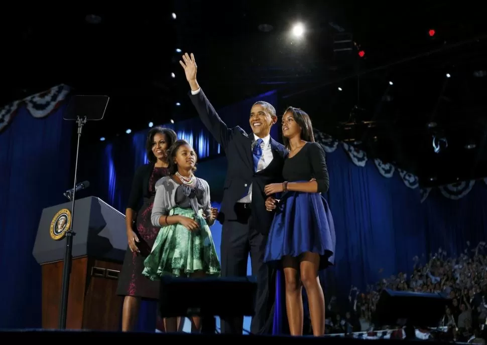 EN CHICAGO. El reelecto presidente saluda a la multitud, al confirmarse el triunfo. Su esposa, Michelle Robinson y sus hijas, Sasha y Malia, lo acompañan. REUTERS