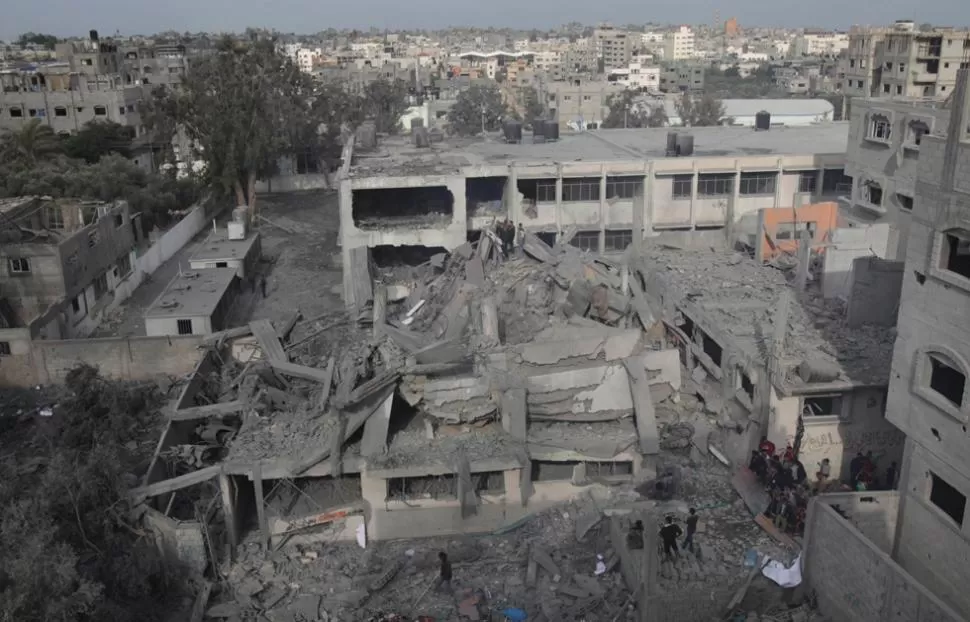 DESTRUIDO. Palestinos recorren los escombros en busca de sobrevivientes. REUTERS.