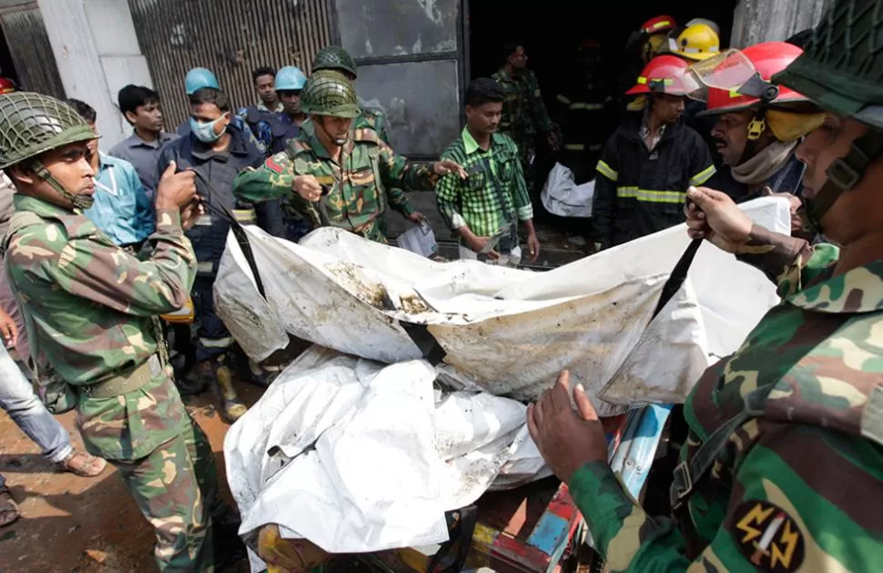 MOMENTOS DE HORROR. Los rescatistas retiran los cuerpos calcinados de la planta textil. REUTERS