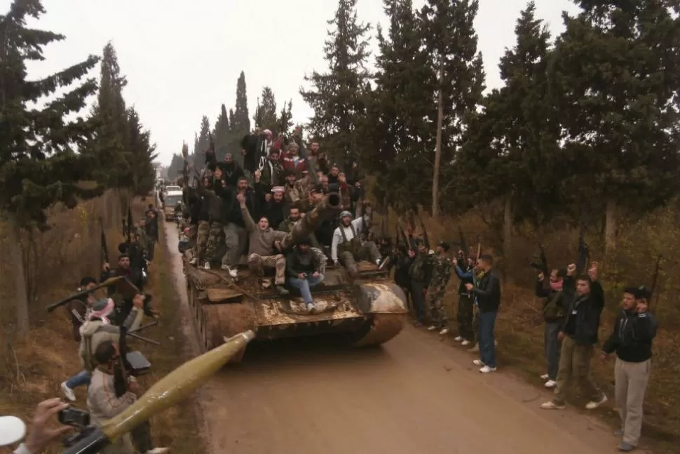 VICTORIOSOS. Soldados rebeldes se pasean en un tanque que capturaron del ejército regular sirio. REUTERS