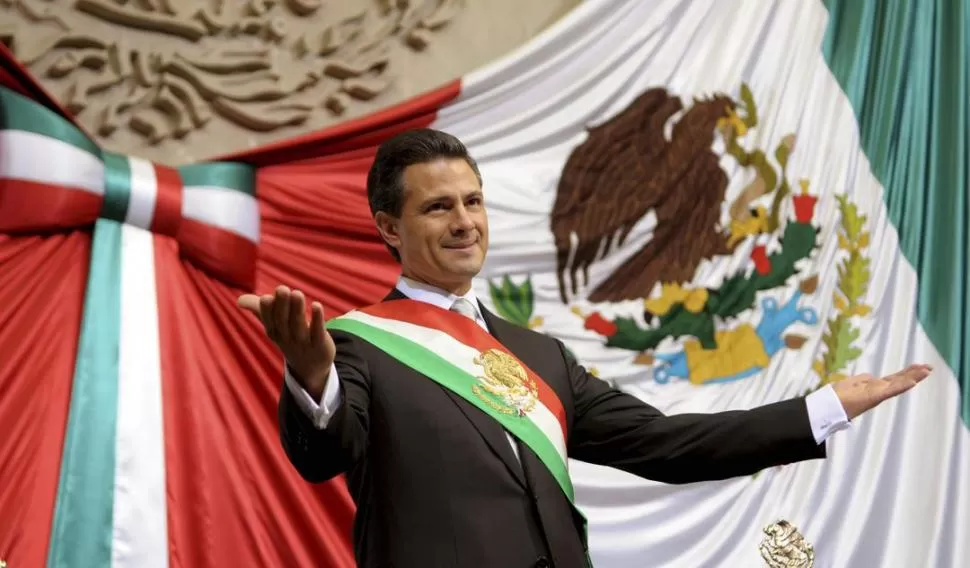 ATRIBUTO DEL MANDO. Peña Nieto saluda a sus seguidores en el Congreso con la banda presidencial sobre su pecho, y delante de la bandera nacional. REUTERS
