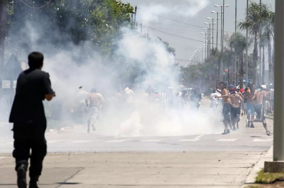 BATALLA. Un policía dispara contra quienes intentaban llegar a Carrefour. REUTERS