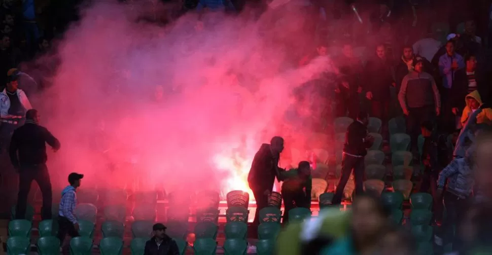 FUEGO EN LAS TRIBUNAS. Hinchas queman bengalas en las gradas del estadio de Port Said, tras el final del partido. AFP