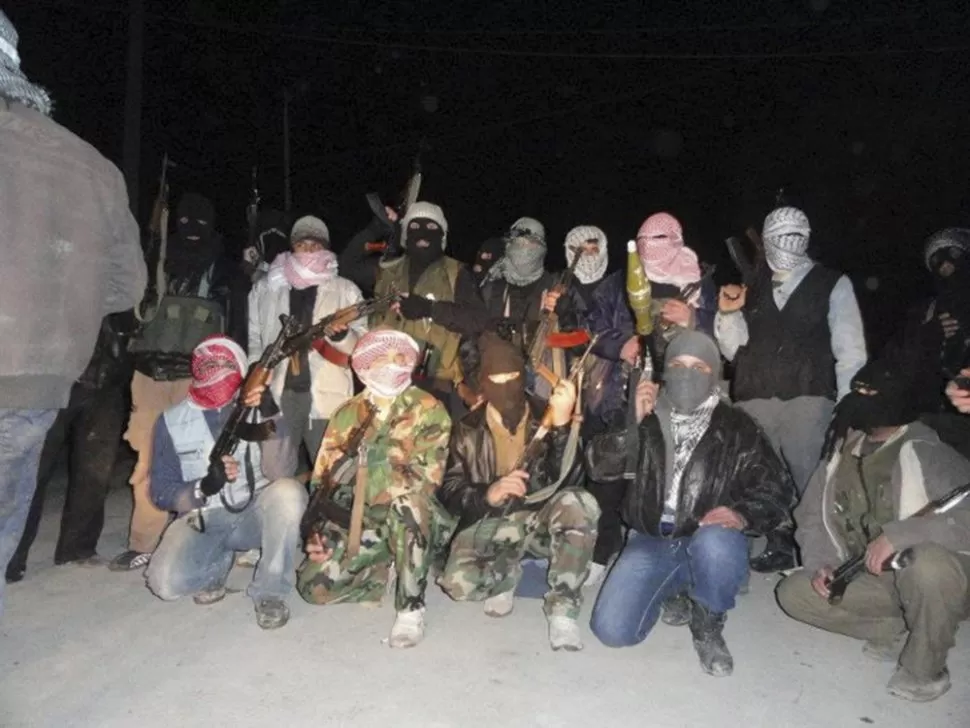 CON LOS ROSTROS CUBIERTOS. Integrantes del Ejército Sirio Libre posan con sus armas cerca de Damasco. REUTERS