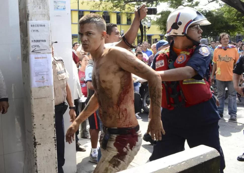 A OTRO LUGAR. La Policía traslada a un herido en los incidentes por el sangriento motín en la cárcel de Uribana. REUTERS
