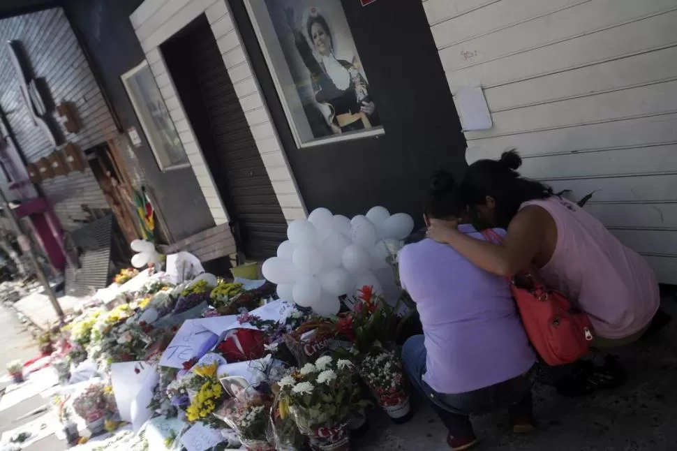 FLORES Y GLOBOS. Dolientes familiares y amigos de los muertos dejaron ofrendas en la puerta del boliche. REUTERS