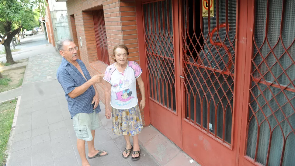 SEGUNDO SUSTO. Esmeralda junto a su esposo, en la puerta de la casa de Bolivia al 500, muestra el vidrio roto. Es la segunda vez que sufren destrozos.