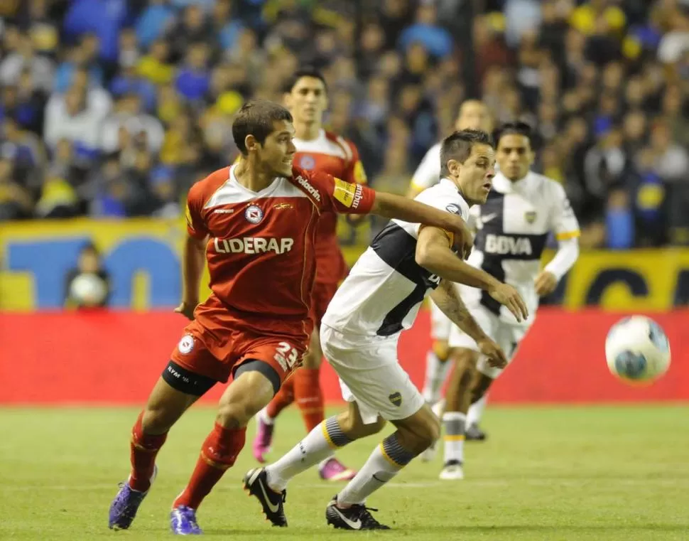 SIN MUCHAS LUCES. Juan Manuel Martínez intenta girar ante la marca implacable de Nicolás Freire, uno de los defensores de Argentinos. El delantero boquense fue reemplazado en el segundo tiempo. 