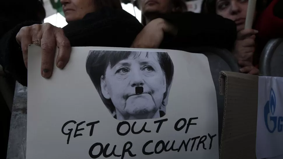 COMO NAZI. Fuera de nuestro país, reza un cartel que pinta a Merkel con el bigote de Hitler. REUTERS