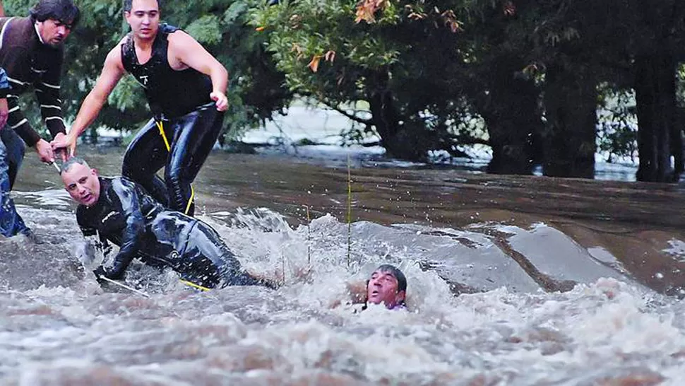 RESCATE EN LA CORRIENTE. Un hombre es salvado por un grupo de voluntarios en medio de la violenta inundación, en pleno centro de Villa Elisa. FOTO TOMADA DE CLARIN.COM/Mauricio Nievas