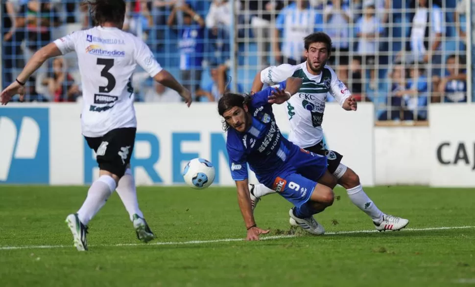 LEJOS DEL ARCO. Cobelli, que intenta cubrir el balón ante la marca de un rival de Sarmiento, no tuvo chances de gol. 