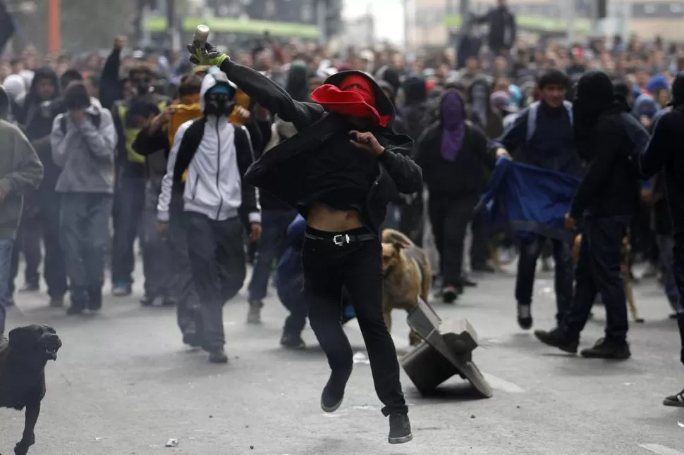 EN SANTIAGO. Un estudiante lanza una botella con pintura a la policía. 