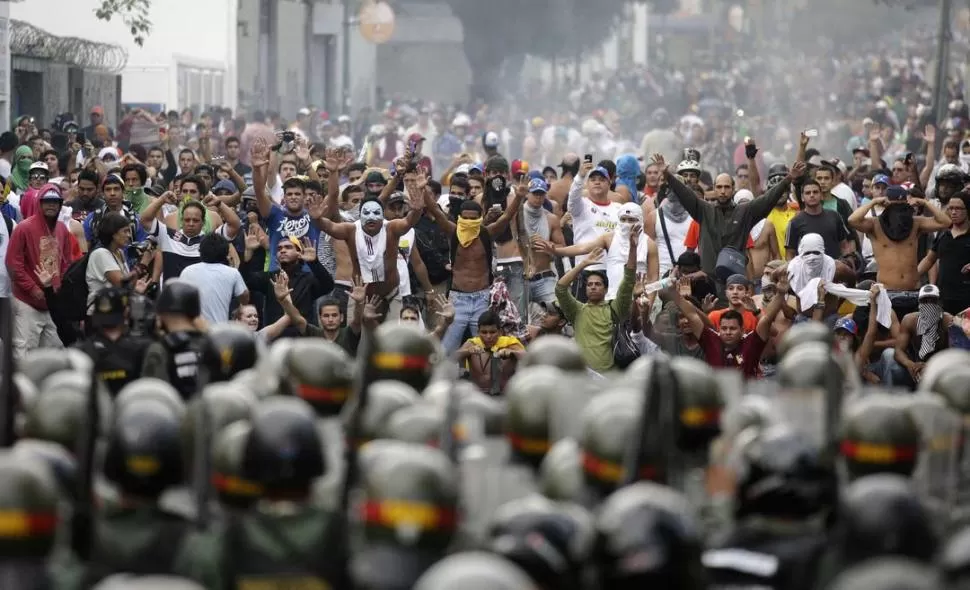 EN CARACAS. Seguidores de Capriles y la policía del gobierno aparecen frente a frente en una calle de la capital. La oposición pide el recuento de los votos y niega legitimidad a Maduro. REUTERS
