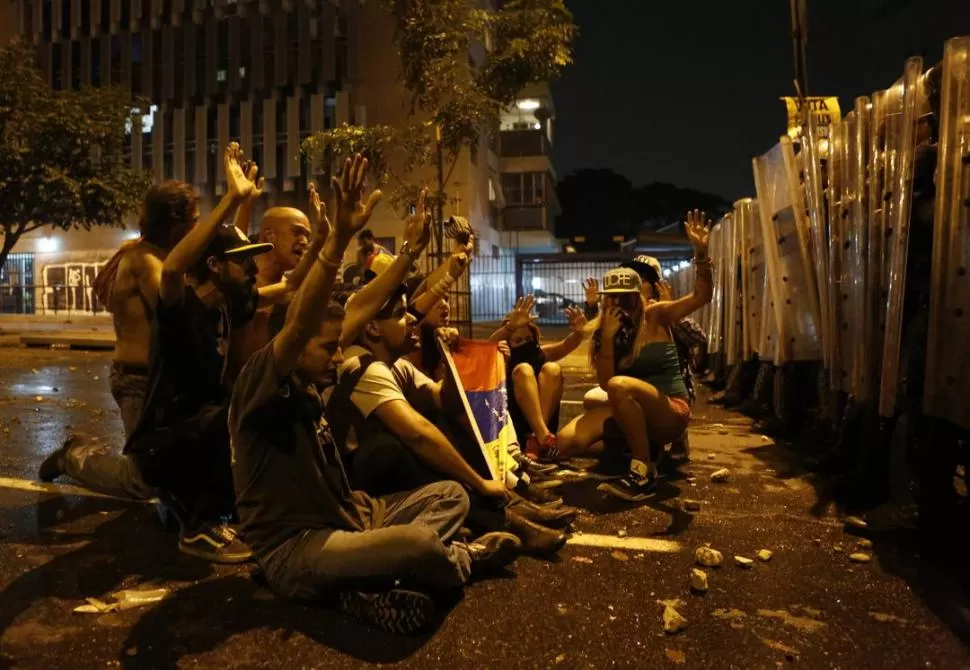 TENSIÓN. Simpatizantes de Capriles que piden el recuento de votos, y la Policía, frente a frente en Caracas. REUTERS