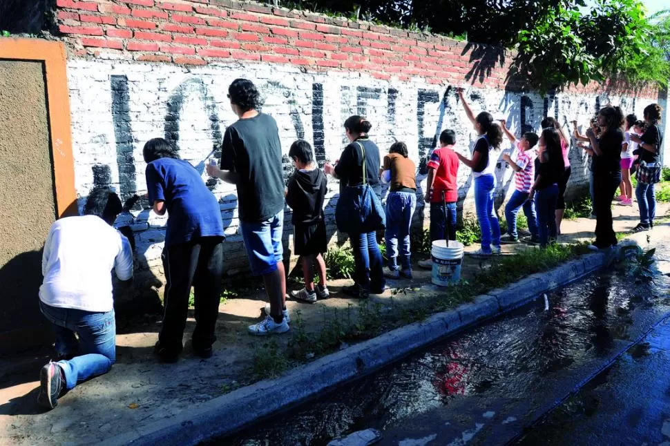MANOS A LA OBRA. Fernando Ríos, mentor de Acción Poética, marcó las letras en las paredes y los vecinos (grandes y chicos) se encargaron de rellenarlas prolijamente. LA GACETA / FOTO DE INéS QUINTEROS ORIO