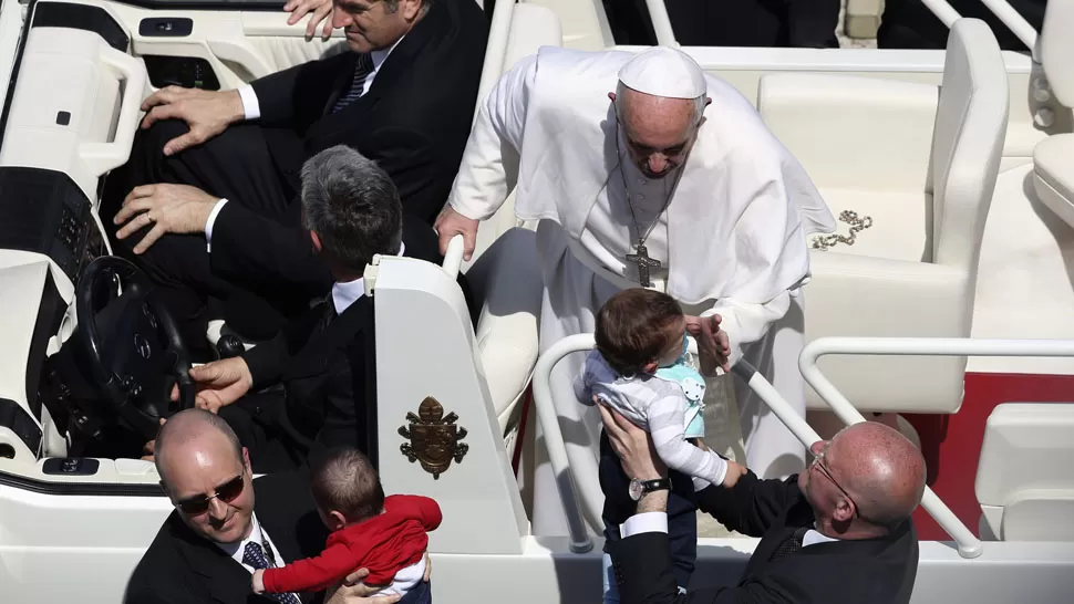 BENDICION. El Papa besa a los niños que le acercan, durante una misa multitudinaria en la Plaza de San Pedro. REUTERS
