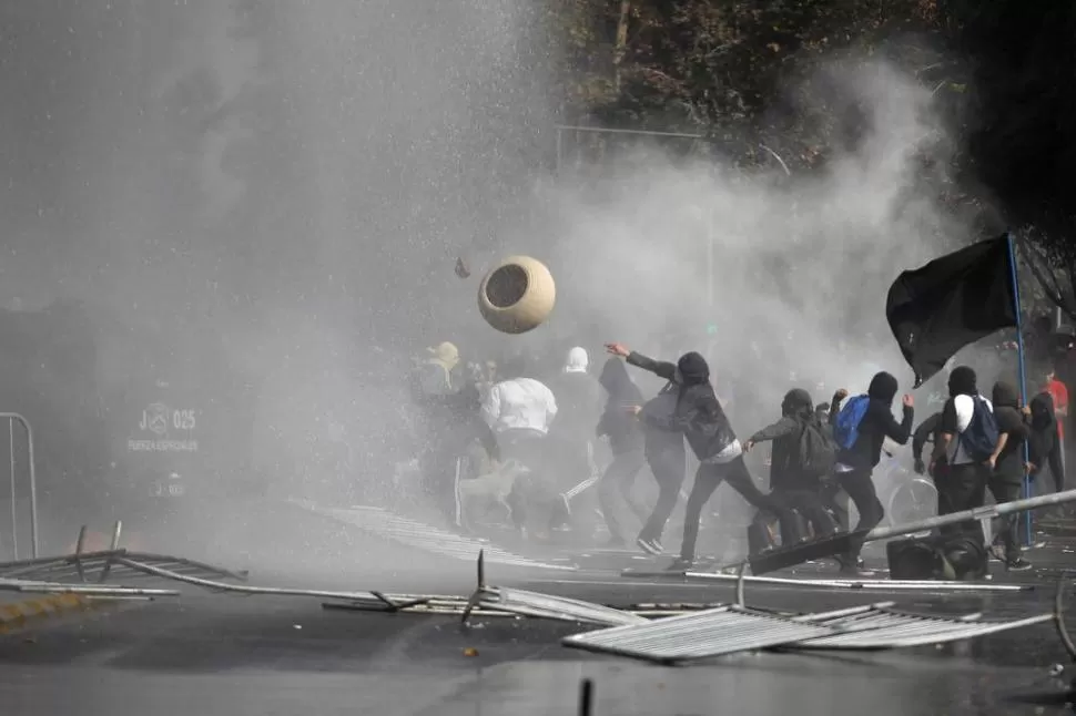 ENFRENTAMIENTOS. Grupos de manifestantes no identificados y Carabineros confrontaron ayer en las calles de la capital chilena, al finalizar un acto. REUTERS