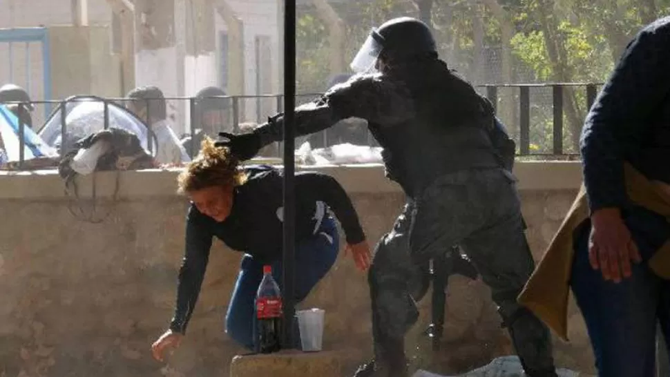 VUELTA AL PAIS. La imagen de un policía tomando de los pelos a una mujer es la cara mostrada por los medios que acompañan la resistencia de los pobladores de Famatina. FOTO TOMADA DE FACEBOOK.COM/RADIO-FM-AMERICA-NOTICIAS-941-LA-RIOJA