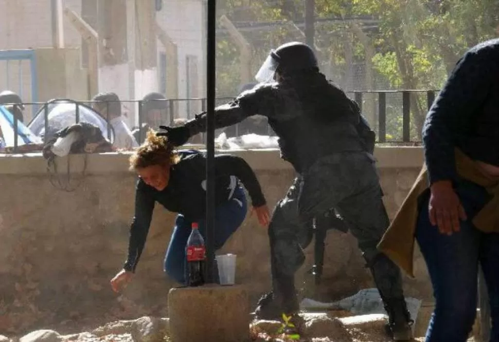 VIOLENCIA. Un policía provincial toma por los pelos a una joven manifestante, durante la refriega entre grupos antiminería y la fuerza de seguridad. FACEBOOK / MUNICIPALIDAD FAMATINA