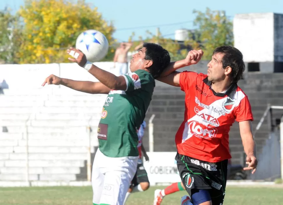 DE PECHO. Juan Paz para la pelota ante la mirada del jugador de Maipú. 
