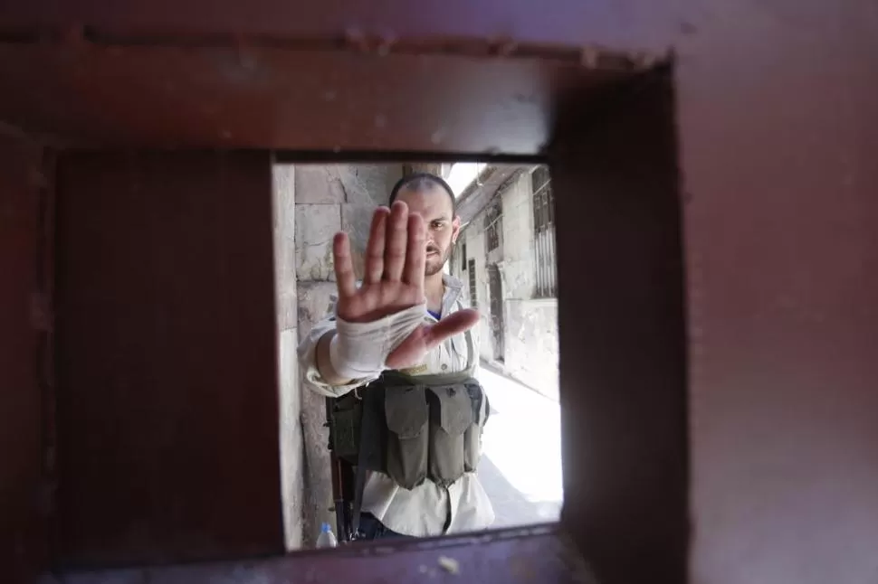 EN EL FRENTE. Un miembro del Ejército de Al Assad no quiere que se saquen fotos de la lucha en Damasco. REUTERS