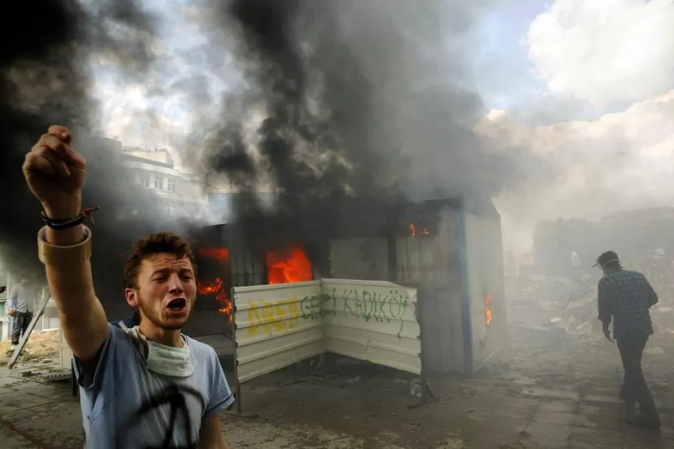 PLAZA TAKSIM DE ESTAMBUL. Uno de los manifestantes antigubernamentales pide ayuda para apagar el incendio de un contenedor. Las protestas se extendieron por toda Turquía. REUTERS 