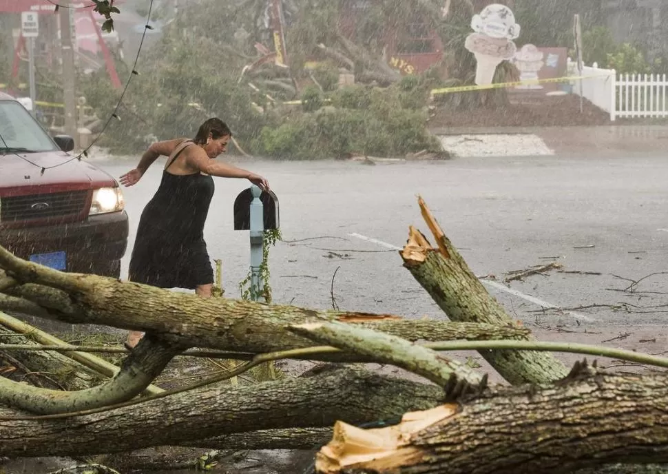 EN FLORIDA. Una mujer trata de cruzar una calle anegada en Gulfport, donde se advierten la caída de árboles y destrozos en las viviendas. REUTERS