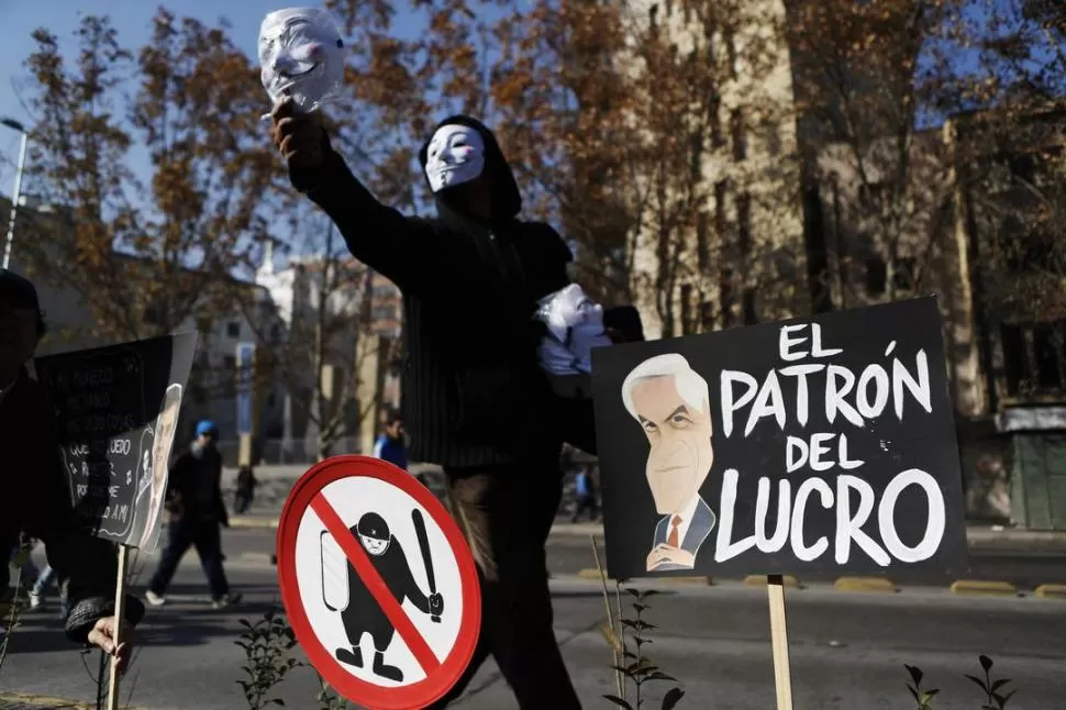 REPUDIO. Un manifestante, junto a carteles contra Piñera y la Policía. REUTERS