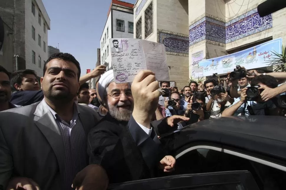 TEHERÁN. El candidato Hassan Rohani muestra sus documentos tras votar. REUTERS