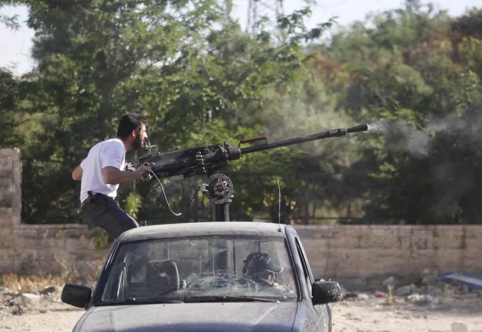 EN ALEPPO. Un combatiente de los grupos rebeldes acciona una ametralladora pesada contra las tropas sirias. REUTERS
