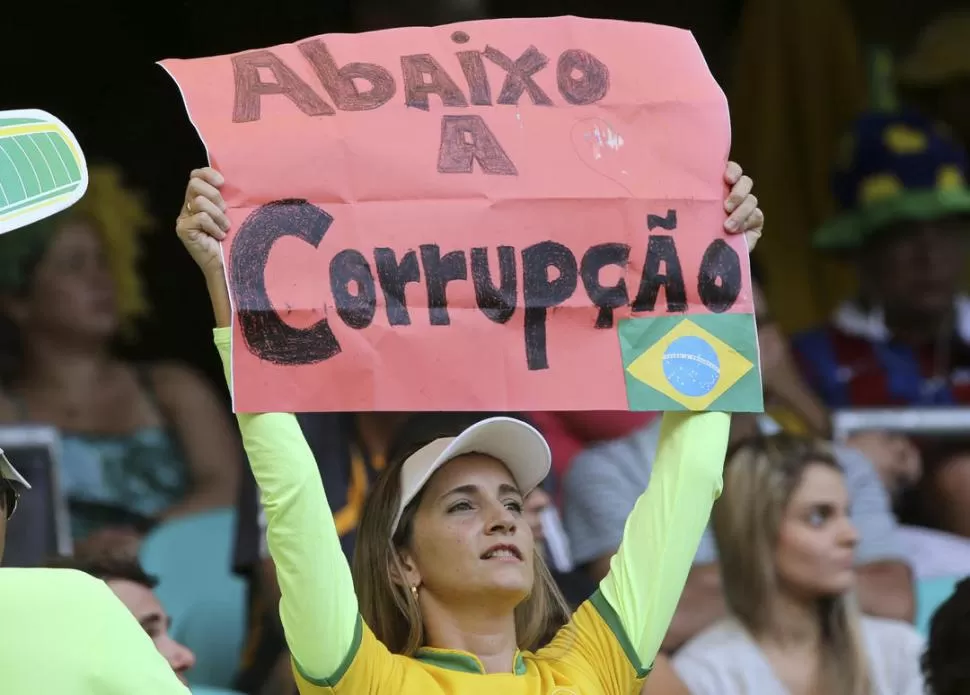 RECLAMO DESDE LA TRIBUNA. Una seguidora de la selección brasileña de fútbol exige el fin de la corrupción, antes del inicio del partido con Italia. REUTERS