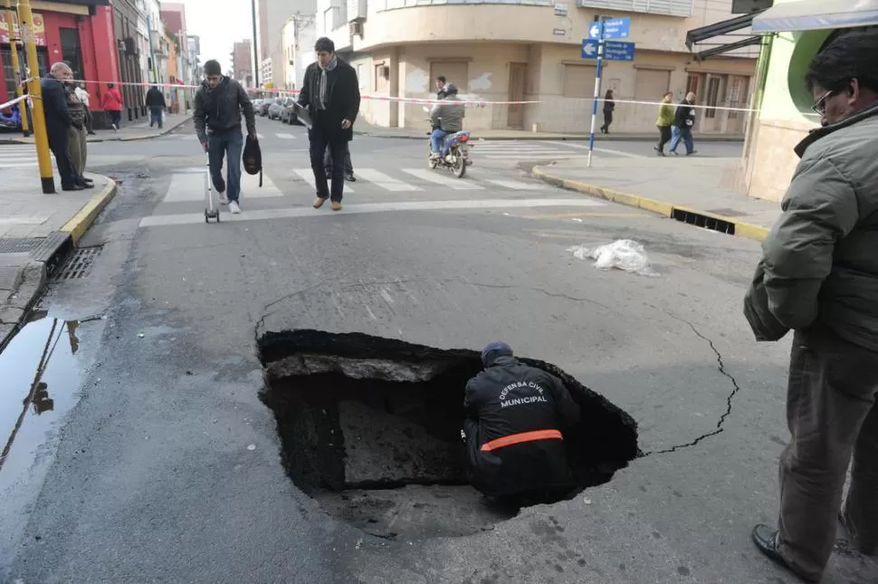 ENORME. Un empleado municipal inspecciona el pozo que apareció a metros de la esquina con Monteagudo. LA GACETA / FOTO DE ANTONIO FERRONI 