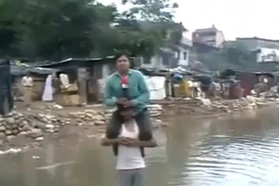 Periodista indio se sube a los hombros de una víctima de las inundaciones para reportar