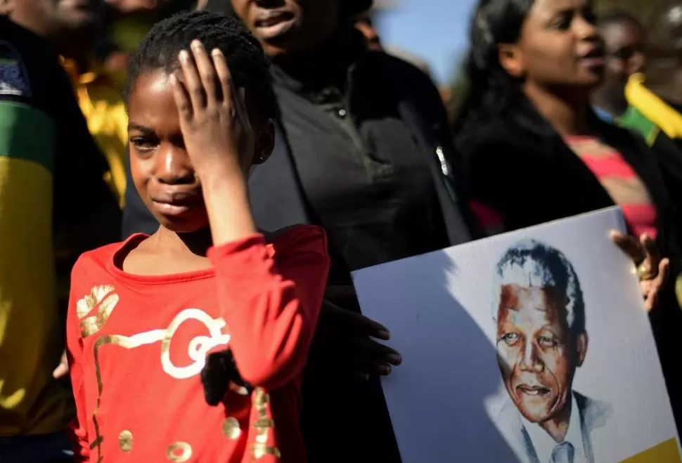 DOLOR Y EMOCIÓN. Una niña llora y su familia busca acercarse al hospital donde está internado Mandela. REUTERS